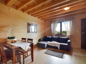 ein Wohnzimmer mit einem Sofa und einem Tisch in der Unterkunft Bursztynowe Domki in Sarbinowo