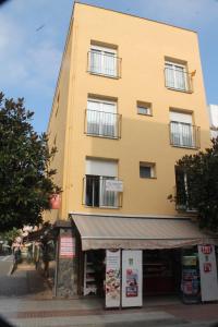 un edificio alto amarillo con una tienda delante en Apartaments Can Claudi, en Tossa de Mar