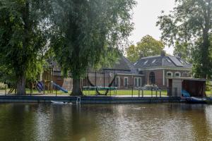 una casa con parque infantil junto a un río en Uitzicht op de haven, en Kollum
