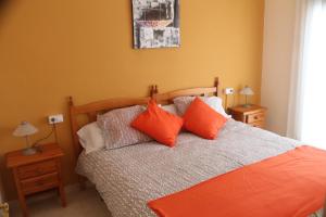 1 dormitorio con 1 cama con almohadas de color naranja en Apartaments Can Claudi, en Tossa de Mar