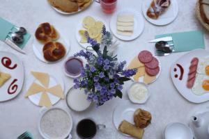 einen Tisch mit Teller mit Lebensmitteln und Blumen darauf in der Unterkunft Sary Arka Hotel in Schymkent