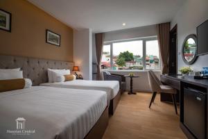 a hotel room with two beds and a desk at Hanoian Central Hotel & Spa in Hanoi