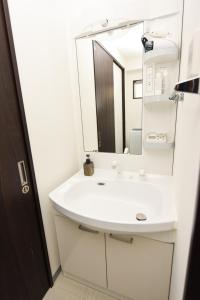 y baño con lavabo blanco y espejo. en EX Itoman Apartment 601, en Itoman