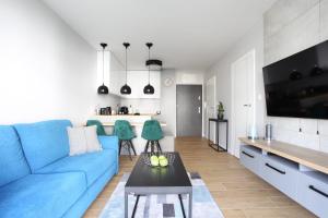 salon z niebieską kanapą i kuchnią w obiekcie Apartament Gardenia Sea&Sun DZIWNÓW PRZY PLAŻY w Dziwnowie