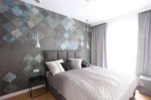 una camera con un letto con una parete grigia di Apartament Gardenia Sea&Sun DZIWNÓW PRZY PLAŻY a Dziwnów