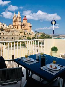 einen blauen Tisch mit zwei Teller Essen auf einem Balkon in der Unterkunft Brand new Mellieha sea view apt with parking in Mellieħa