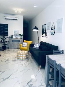 a living room with a black couch and a yellow chair at Brand new Mellieha sea view apt with parking in Mellieħa