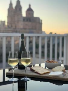 a table with two glasses of white wine and a bottle at Brand new Mellieha sea view apt with parking in Mellieħa
