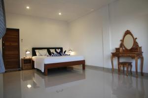 a bedroom with a bed and a mirror and a table at Karma Amed Guesthouse in Amed