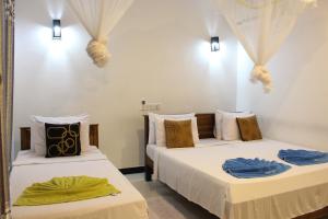 a hotel room with two beds and two lamps at Sigiri Saman Home Stay in Sigiriya