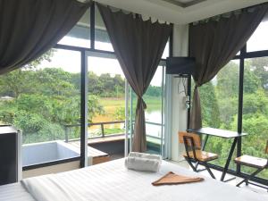Nava Tara Resort في Takua Pa: غرفة نوم بسرير ونافذة كبيرة