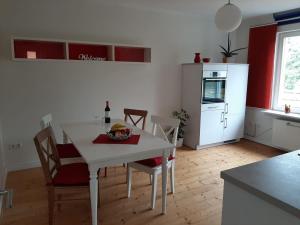 een keuken met een witte tafel en stoelen en een witte koelkast bij Ferienwohnung Neumann in Kassel