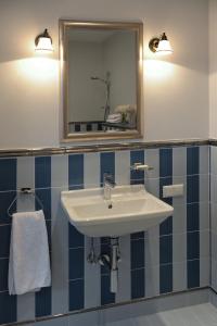 bagno con lavandino bianco e specchio di Ursula Royal Apartments a Druskininkai