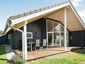 ein Haus mit einer Terrasse mit einem Tisch und Stühlen in der Unterkunft Holiday Home As Hedegård II in Sønderby