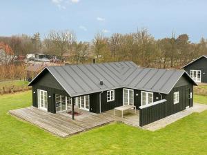 a black house with a wooden deck in a field at 8 person holiday home in Nysted in Nysted