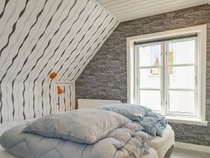 a bedroom with a large bed with a brick wall at 5 person holiday home in R nne in Rønne