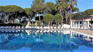 una piscina de agua con sillas blancas y árboles en Studio 4 personnes, climatisé, rez de jardin, en Saint-Raphaël