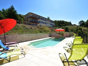 a pool with chairs and umbrellas and a building at Spacious Holiday Home with Swimming Pool in Cuzy in Cuzy