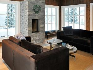 a living room with leather furniture and a stone fireplace at 12 person holiday home in F vang in Favang