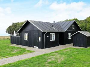 a black house with a black roof at 8 person holiday home in Nysted in Nysted