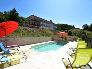 a pool with chairs and umbrellas and a building at Modern apartment in Cuzy with shared pool in Cuzy