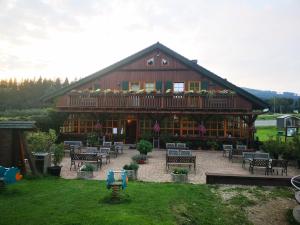a large wooden building with tables and chairs in a yard at Apartments Haltmar in Ostružná