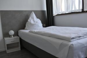 Una cama blanca con una almohada encima. en Motel Schönefeld, en Großziethen