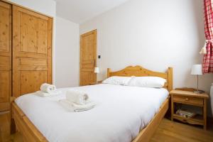 Un dormitorio con una cama blanca con toallas. en APARTMENT STADDON - Alpes Travel - Central Chamonix - Sleeps 4-6, en Chamonix-Mont-Blanc