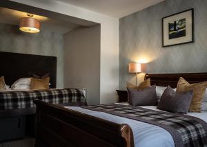 a hotel room with two beds and two lamps at Beaufort Hotel in Inverness