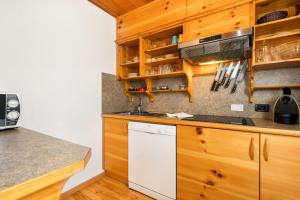 a kitchen with wooden cabinets and a white dishwasher at Apartments Antares in Colfosco