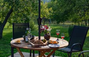 a wooden table with a plate of food and wine glasses at Mednieki Kalvene in Krusāti