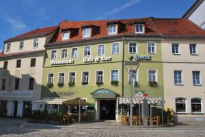 un grand bâtiment jaune et vert dans une rue dans l'établissement Hotel Evabrunnen, à Bischofswerda
