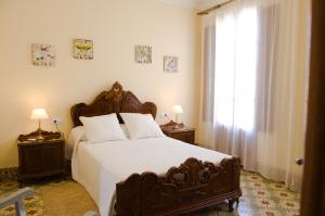 a bedroom with a large bed with white sheets and a window at Cas Padri Font in Petra