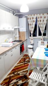 クルジュ・ナポカにあるUltra Central - Stunning Two Bedroom Apartmentの白いキャビネット、テーブルと椅子付きのキッチンが備わります。