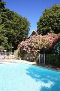 a swimming pool with a fence and pink flowers at Hôtel le Chalet Fleuri in Saint-Rémy-de-Provence