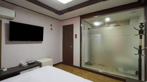 a bedroom with a shower and a television on the wall at Keumkang Motel in Seoul