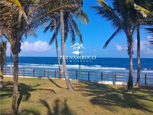 uma placa na praia com palmeiras e o oceano em Beach Class Muro Alto - Porto de Galinhas em Porto de Galinhas