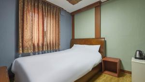 una camera da letto con un grande letto bianco e una finestra di Keumkang Motel a Seul