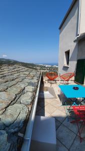 a patio with chairs and a table on a rock wall at A Casetta di SANTA MARIA in Furiani