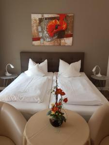 2 Betten mit weißer Bettwäsche und einem Tisch mit Blumen in der Unterkunft Villa zur schönen Aussicht in Bad Salzuflen