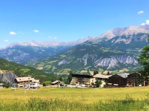 un pueblo en un campo con montañas en el fondo en Hôtel Soleil des Neiges, en Le Sauze