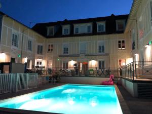 - une piscine en face d'un bâtiment la nuit dans l'établissement Boutique Hôtel d'Orbigny Chatelaillon - La Rochelle, à Châtelaillon-Plage