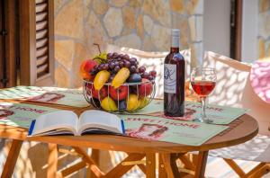 een tafel met een fruitschaal en een fles wijn bij Sweet home apartment in Gaios