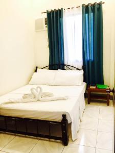 a bedroom with two beds with white sheets and blue curtains at Lindstrom's Inn in Panglao
