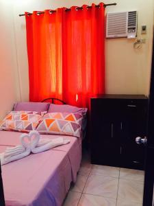 um quarto com 2 camas e cortinas vermelhas em Lindstrom's Inn em Panglao