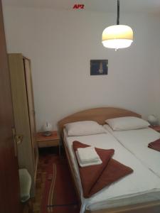 ein Schlafzimmer mit einem Bett mit weißen Kissen und einer Lampe in der Unterkunft Apartments Šudić in Njivice