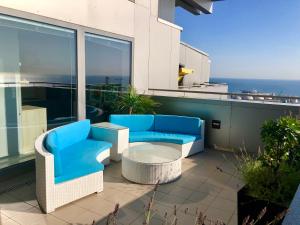 a patio with blue chairs and a table on a balcony at SEA TOWERS PENTHOUSE 23-24 Two-Floors Sea View Panoramic Terrace 110m2 !!! jacuzzi in Gdynia