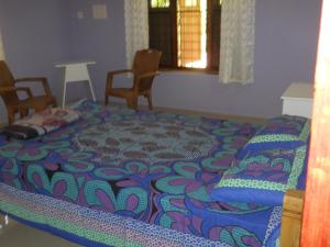 Bett in einem Zimmer mit Stühlen und Fenster in der Unterkunft CoconutCrazy! Homestay in Ottappālam
