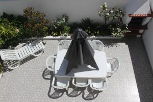 a white table and chairs with a black cape on it at Baleal Holiday House in Baleal