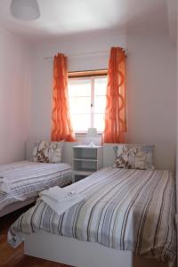 1 dormitorio con 2 camas y una ventana con cortinas de color naranja en Baleal Holiday House, en Baleal
